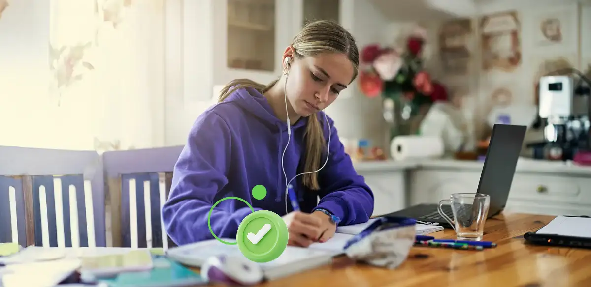 Student taking notes at home with her laptop and notebook